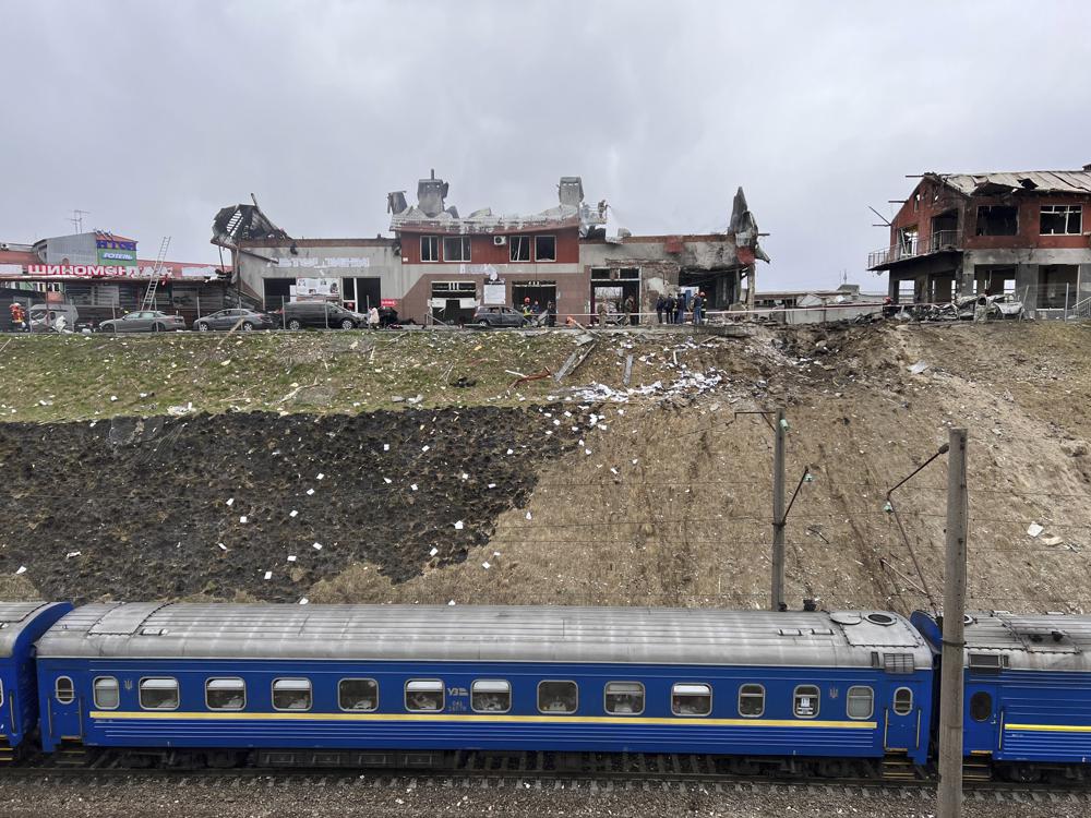 Un tren que viaja desde Dnipro pasa por el área donde los trabajadores de emergencia limpian los escombros después de que un ataque aéreo golpeó una tienda de neumáticos en la ciudad occidental de Lviv, Ucrania, el lunes 18 de abril de 2022. Misiles rusos alcanzaron la ciudad de Lviv en el oeste de Ucrania el lunes. matando al menos a seis personas, dijeron funcionarios ucranianos, mientras las tropas de Moscú intensificaban los ataques a la infraestructura en preparación para un ataque total en el este.  (Foto AP/Philip Crowther)