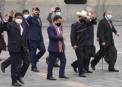 El presidente peruano Pedro Castillo, con sombrero, saluda junto al primer ministro Guido Bellido, centroizquierda, y los miembros de su gabinete en el palacio de gobierno mientras Bellido y los otros ministros parten hacia el Congreso para pedirle a los legisladores un voto de confianza en Lima, Perú, el jueves 26 de agosto de 2021. (AP Foto/Martín Mejía)