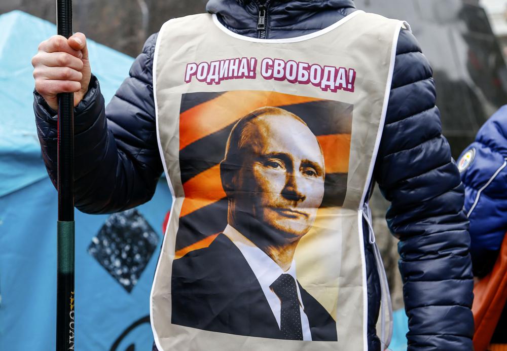 FILE - A pro-Russia demonstrator wears a vest bearing a depiction of Russian President Vladimir Putin and the words, "Motherland! Freedom!" during a rally in Donetsk, Ukraine, Sunday, March 16, 2014. Pro-Russia demonstrators in the eastern city of Donetsk called for a referendum similar to the one in Crimea. (AP Photo/Andrey Basevich, File)