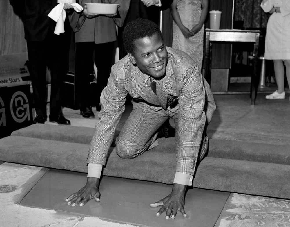 REMOVES REFERENCE TO THE BAHAMAS - FILE -  Sidney Poitier, star of "To Sir With Love," places his hands in wet cement at Grauman's Chinese Theater in Los Angeles on  June 23, 1967.  Poitier, the groundbreaking actor and enduring inspiration who transformed how Black people were portrayed on screen, became the first Black actor to win an Academy Award for best lead performance and the first to be a top box-office draw, died Thursday, Jan. 6, 2022. He was 94. (AP Photo/File)