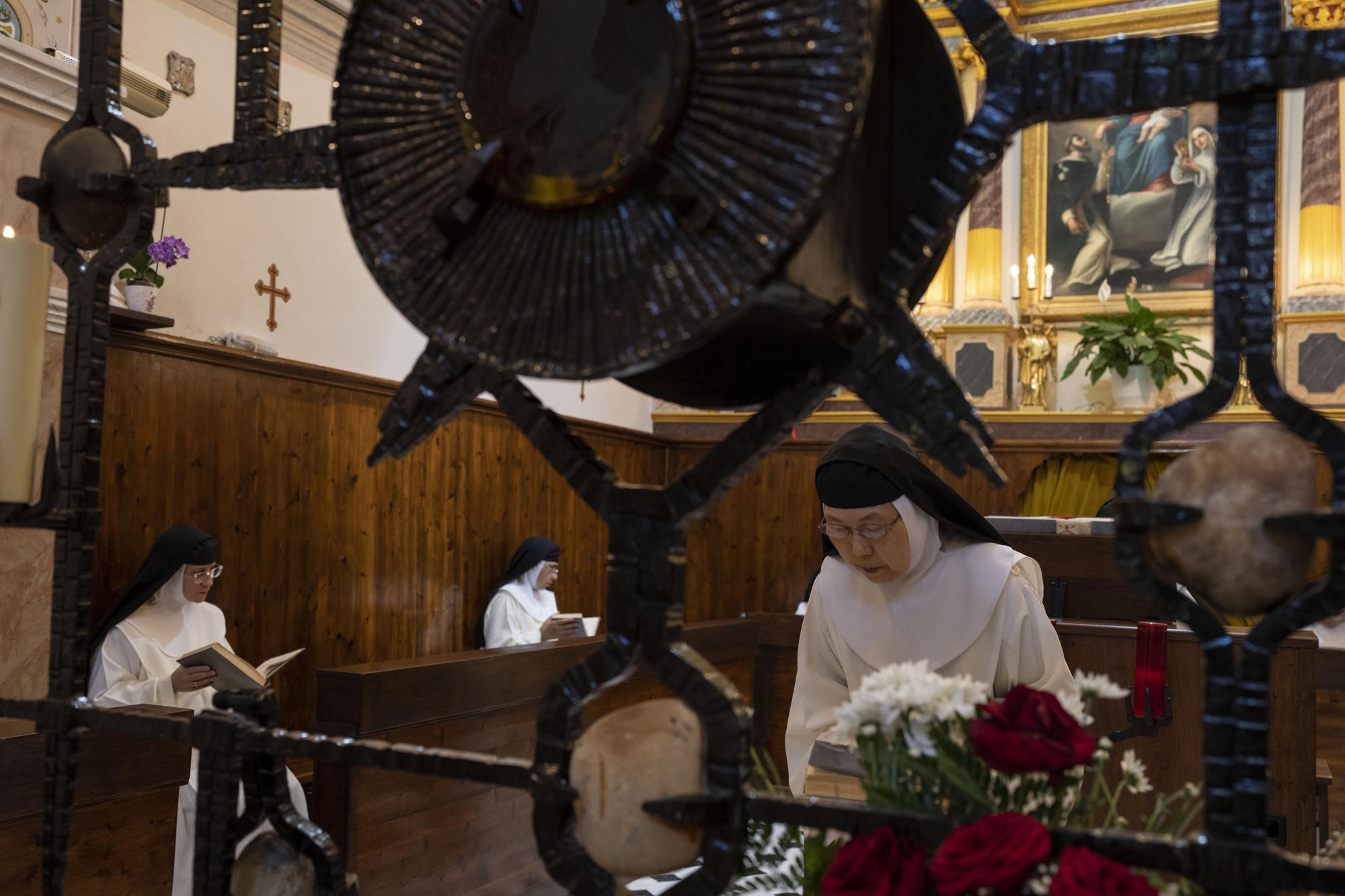 La hermana María de Jesús inclina la cabeza mientras la hermana María Flor de la Eucaristía, al frente a la izquierda, y la hermana Amparo de María rezan durante la misa en el monasterio católico de Santa Catalina en la isla griega de Santorini el martes 14 de junio de 2022. Las monjas orar por lo menos nueve horas al día, la mayor parte cantada en latín, español y griego.  (Foto AP/Petros Giannakouris)