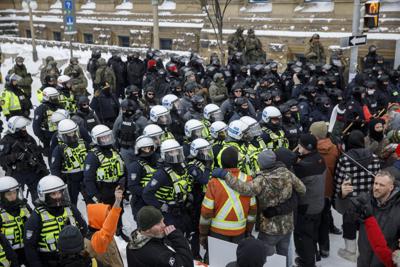 Policías antimotines hacen retroceder a los manifestantes en un intento por poner fin a las protestas contra las medidas del gobierno ante el COVID-19 en Ottawa, el sábado 19 de febrero de 2022. (Cole Burston /The Canadian Press vía AP)