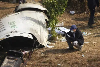 Un investigador francés toma una foto de los restos de un avión de pasajeros estrellado en Pokhara, Nepal, miércoles 18 de enero de 2023. El avión se estrelló el domingo pasado y murieron las 72 personas a bordo. (AP Foto/Yunish Gurung)