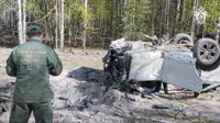 This image taken from video released by the Russian Investigative Committee on Saturday, May 6, 2023, shows a Russian Investigative Committee employee working at the site of the exploded car of Russian writer and publicist Zakhar Prilepin in the region of Nizhny Novgorod, about 400 kilometers (250 miles) east of Moscow. Russian state news agency Tass says the car of Prilepin exploded on Saturday, injuring him and killing his driver. (Russian Investigative Committee via AP)