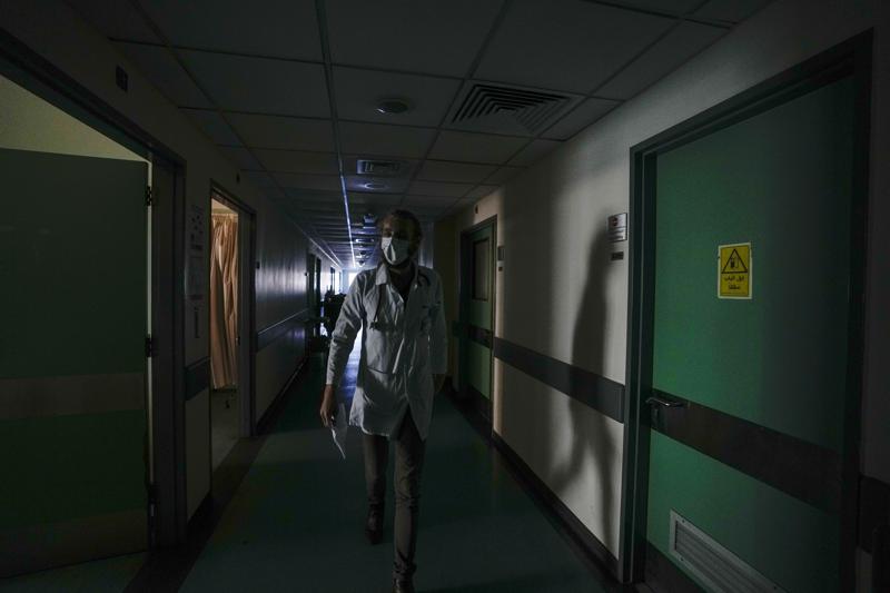 A doctor walks through a corridor of the government-run Rafik Hariri University Hospital during a power outage in Beirut, Lebanon, Wednesday, Aug. 11, 2021.  Many private hospitals, who offer 80% of Lebanon's medical services, are shutting down because of lack of resources or turning away patients who can't pay. (AP Photo/Hassan Ammar)