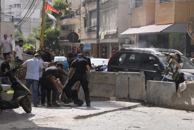 Partidarios de un grupo chií aliado con Hezbolá ayudan a un compañero herido durante los enfrentamientos armados que estallaron durante una protesta en el suburbio de Dahiyeh, en el sur de Beirut, el jueves 14 de octubre de 2021. (AP Foto/Hassan Ammar)