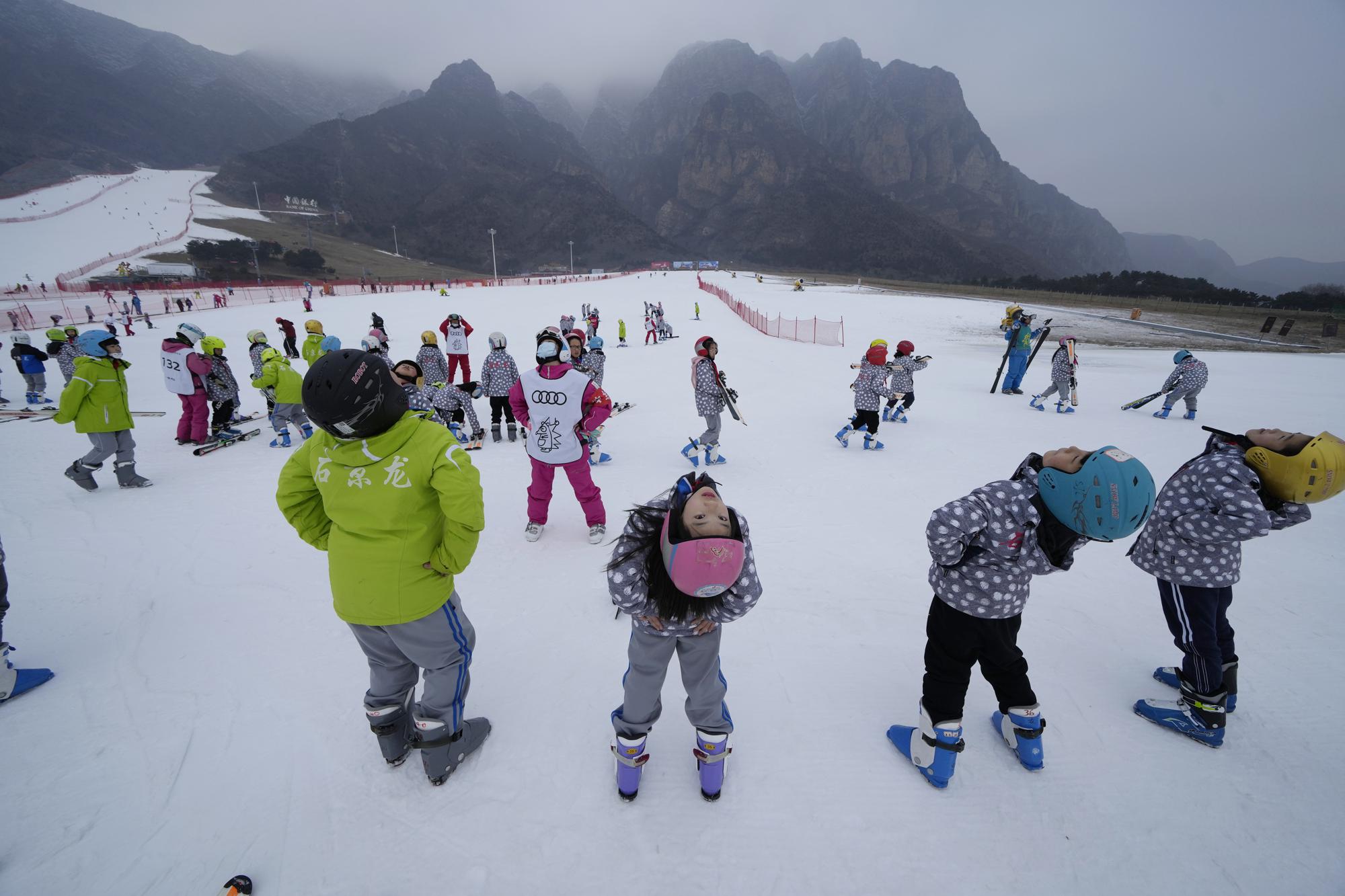 School children warm up before ski lessons at the Vanke Shijinglong Ski Resort in Yanqing on the outskirts of Beijing, China, Thursday, Dec. 23, 2021. The Beijing Winter Olympics is tapping into and encouraging growing interest among Chinese in skiing, skating, hockey and other previously unfamiliar winter sports. It's also creating new business opportunities. (AP Photo/Ng Han Guan)