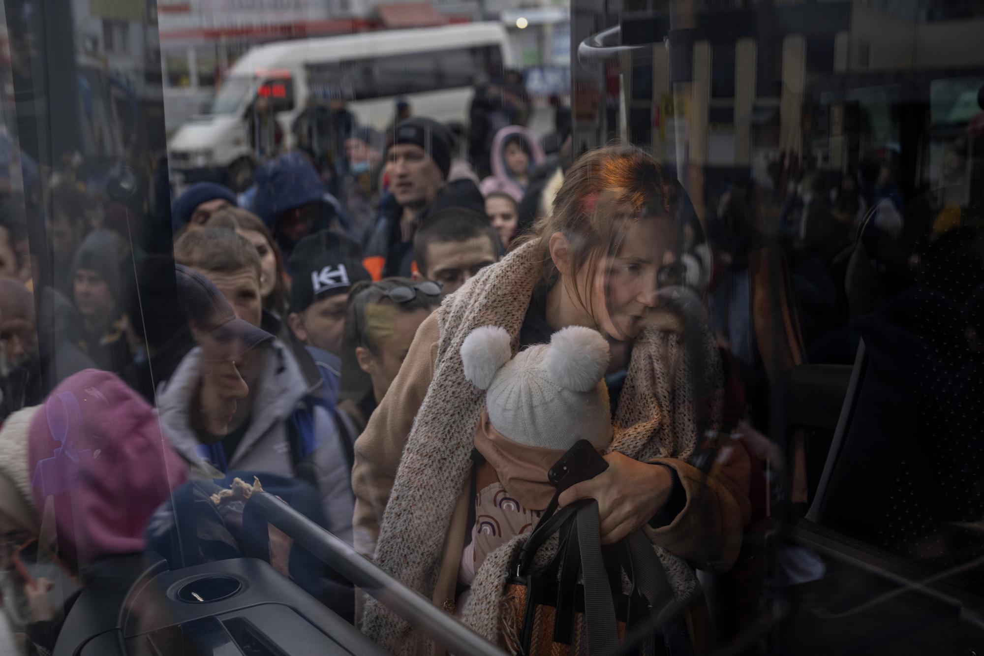 FILE - A woman holds her baby as she gets on a bus leaving Kyiv, Ukraine, Feb. 24, 2022. (AP Photo/Emilio Morenatti)