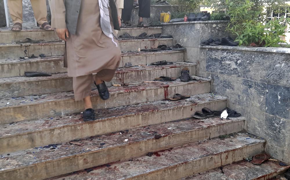 A man walks down blood-stained steps of a mosque following a bombing in Kunduz province, northern Afghanistan, Friday, Oct. 8, 2021. A powerful explosion in a mosque frequented by a Muslim religious minority in northern Afghanistan on Friday has left several casualties, witnesses and the Taliban's spokesman said. (AP Photo/Abdullah Sahil)