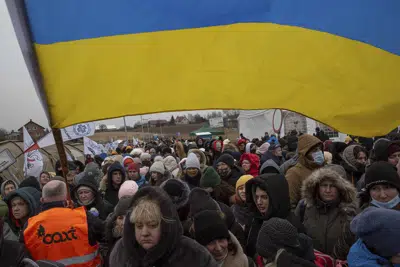 A Ukrainian volunteer Oleksandr Osetynskyi, 44 holds a Ukrainian flag and directs hundreds of refugees after fleeing from the Ukraine and arriving at the border crossing in Medyka, Poland, Monday, March 7, 2022. This was the year war returned to Europe, and few facets of life were left untouched. Russia’s invasion of its neighbor Ukraine unleashed misery on millions of Ukrainians, shattered Europe’s sense of security, ripped up the geopolitical map and rocked the global economy. The shockwaves made life more expensive in homes across Europe, worsened a global migrant crisis and complicated the world’s response to climate change. (AP Photo/Visar Kryeziu)