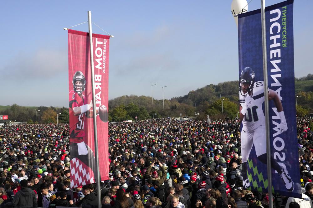 A crowd of thousands of people wait in front of the stadium prior to NFL match between Tampa Bay Buccaneers and Seattle Seahawks at the Allianz Arena in Munich, Germany, Sunday, Nov. 13, 2022. (AP Photo/Markus Schreiber)