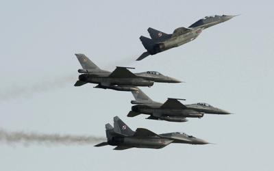 FILE - Two Polish Air Force Russian made Mig 29's fly above and below two Polish Air Force U.S. made F-16's fighter jets during the Air Show in Radom, Poland, on Aug. 27, 2011. In a private video call with American lawmakers over the weekend, Ukrainian President Volodymyr Zelenskyy made a “desperate” plea to the United States to help Kyiv get more warplanes to fight Russia's invasion and retain control of its airspace. (AP Photo/Alik Keplicz, File)
