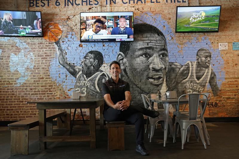 Bret Oliverio poses at his Sup Dogs restaurant in Chapel Hill, N.C., Thursday, July 15, 2021. Oliverio wants to pursue deals with college athletes to endorse his restaurant specializing in hot dogs and burgers along the main Franklin Street drag steps from the University of North Carolina. Like other small-business owners in college towns, he has to sort out what that entails with athletes free to profit from use of their name, image and likeness (NIL) for the first time. (AP Photo/Gerry Broome)