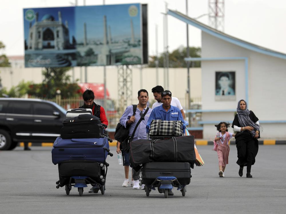 Passengers walk to the departures terminal of Hamid Karzai International Airport in Kabul, Afghanistan, Saturday, Aug. 14, 2021. As a Taliban offensive encircles the Afghan capital, there's increasingly only one way out for those fleeing the war, and only one way in for U.S. troops sent to protect American diplomats still on the ground: the airport. (AP Photo/Rahmat Gul)