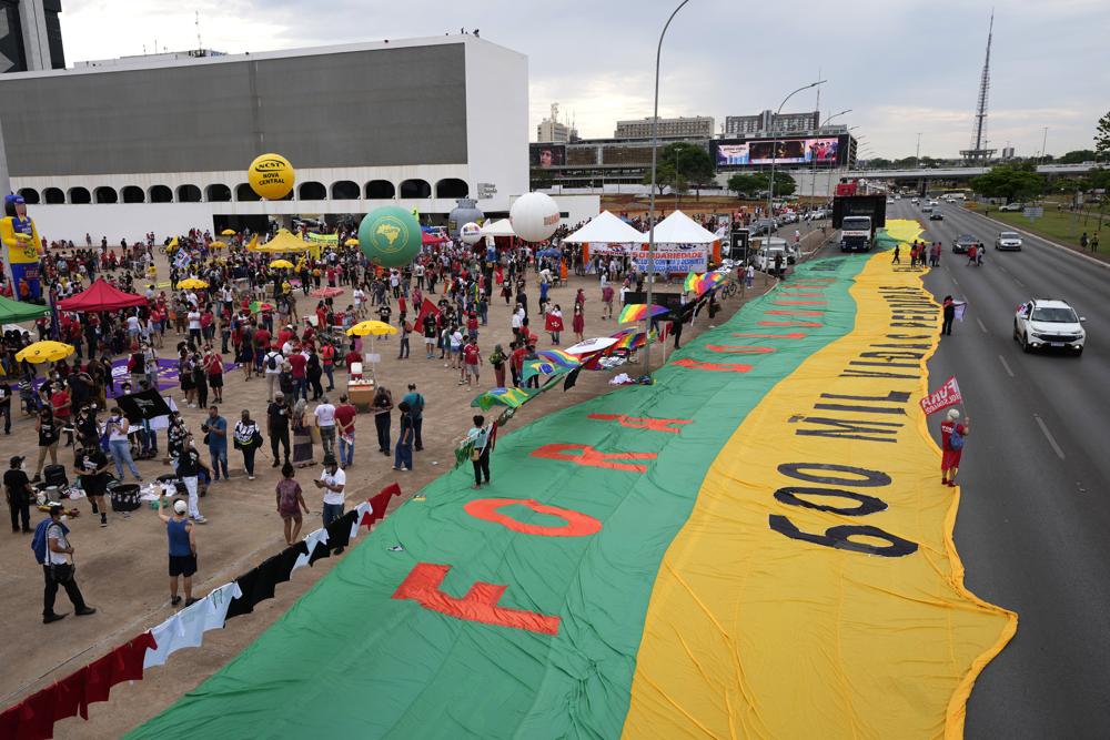 FILE - In this Oct. 2, 2021 file photo, a banner with a message that reads in Portuguese: "Out Bolsonaro, 600 thousand lives lost", stretches alongside a boulevard during a protest against President Jair Bolsonaro calling for his impeachment over his government's handling of the pandemic and accusations of corruption in the purchases of COVID-19 vaccines, in in Brasilia, Brazil. (AP Photo/Eraldo Peres, File)