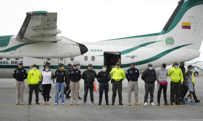 La policía presenta a los medios de comunicación a cinco personas acusadas del asesinato del fiscal de Paraguay para casos de crimen organizado y narcotráfico, Marcelo Pecci, en la pista de un aeropuerto en Bogotá, Colombia, el miércoles 8 de junio de 2022. Pecci fue asesinado el 12 de mayo por hombres armados en una playa colombiana al sur de Cartagena mientras estaba de luna de miel.  (AP Foto/Fernando Vergara)