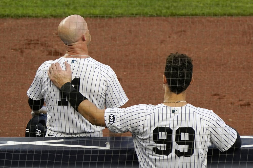 Aaron Judge, de los Yankees de Nueva York, pone su brazo sobre la espalda de Brett Gardner mientras Gardner se toma un descanso durante un cambio de pitcheo en la novena entrada de un juego de la MLB contra los Marlins de Miami, el domingo 27 de septiembre de 2020.