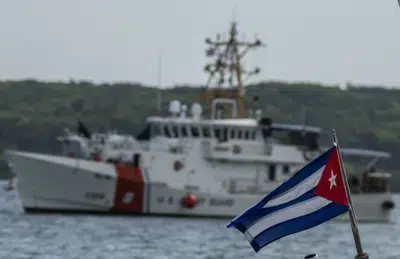 ARCHIVO - En esta foto de archivo del 29 de junio de 2021, se ve una bandera de Cuba de un bote de patrulla fronteriza cubano mientras el barco Charles Sexton de la Guardia Costera de Estados Unidos llega para entregar a cubanos deportados ante las autoridades en la Bahía de Orozco en Artemisa, Cuba. Cuba recibió 2.165 migrantes repatriados de la Guardia Costera a finales del primer trimestre de 2023, reportó un medio cubano el lunes 3 de abril de 2023. (AP Foto/Ramón Espinosa, Archivo)