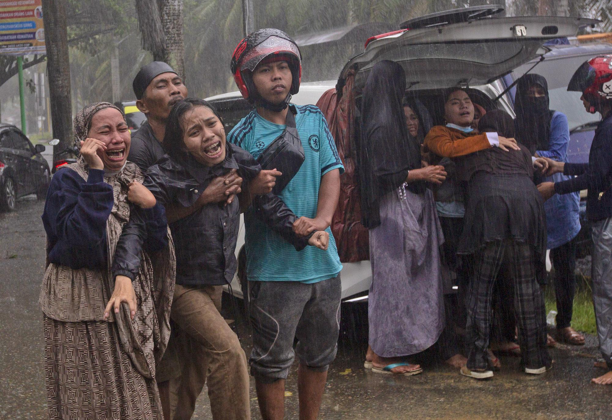 People cry out as the body of their relative is recovered from the rubble of a building damaged by an earthquake in Mamuju, West Sulawesi, Indonesia, on Jan. 15, 2021. (AP Photo/Yusuf Wahil)