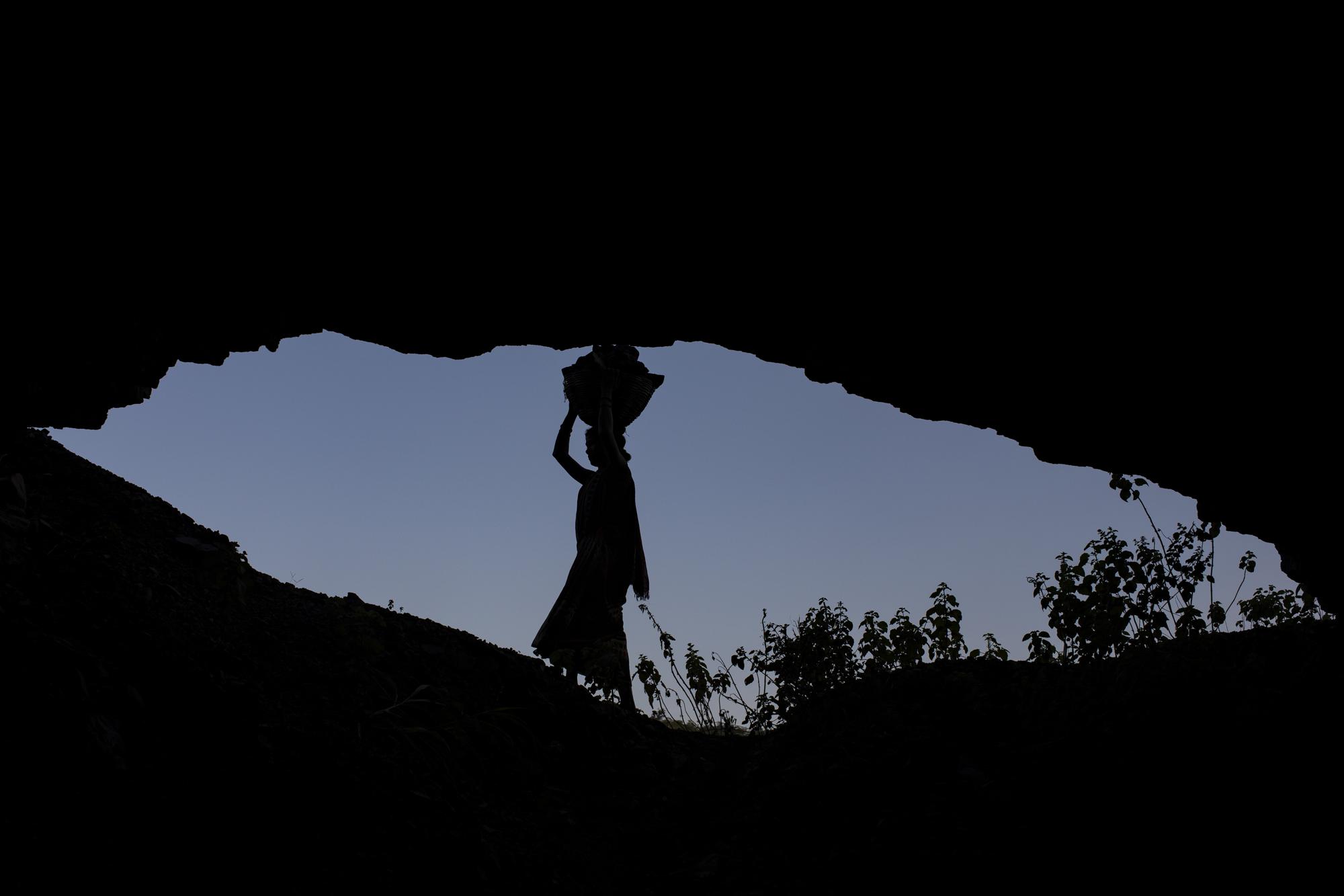 A woman is silhouetted as she carries a basket of coal scavenged from a mine near Dhanbad, an eastern Indian city in Jharkhand state, Friday, Sept. 24, 2021. A 2021 Indian government study found that Jharkhand state -- among the poorest in India and the state with the nation’s largest coal reserves -- is also the most vulnerable Indian state to climate change. Efforts to fight climate change are being held back in part because coal, the biggest single source of climate-changing gases, provides cheap electricity and supports millions of jobs. It's one of the dilemmas facing world leaders gathered in Glasgow, Scotland this week in an attempt to stave off the worst effects of climate change. (AP Photo/Altaf Qadri)