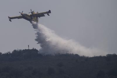 Un avión deja caer agua durante unas labores para extinguir un incendio cerca de Tabara, en el noroeste de España, el miércoles 20 de julio de 2022. (AP Foto/Bernat Armangue)