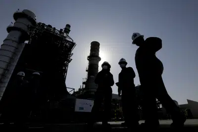 Ingenieros de la petrolera estatal saudí Aramco caminan frente a un generador de turbina de gas en el campo petrolero de Khurais durante una gira para periodistas, al este-noreste de Riad, Arabia Saudí, el 28 de junio de 2021. (AP Foto/Amr Nabil, Archivo)