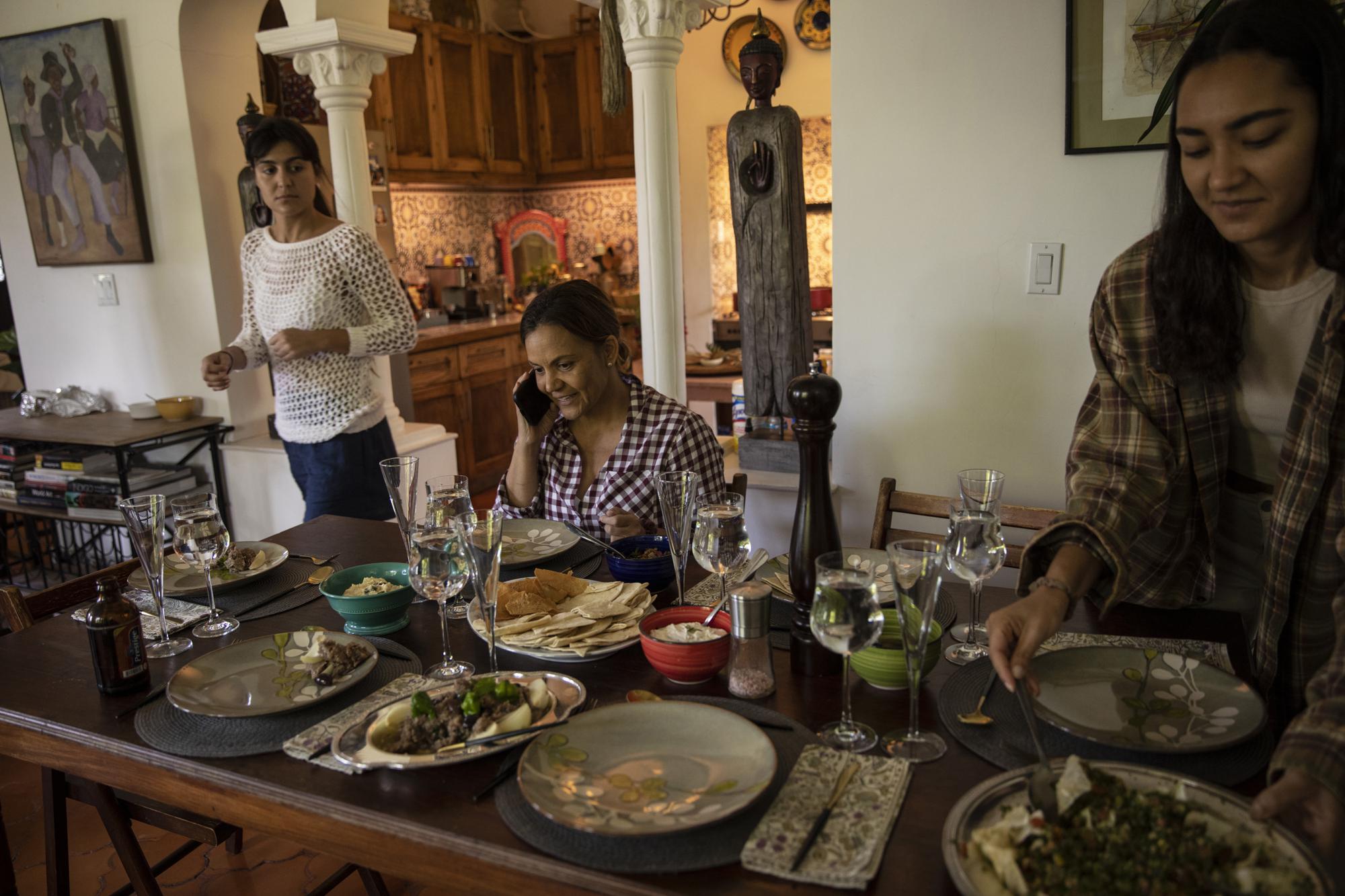 Businesswoman Youri Mevs talks on her cellphone as she sits to have lunch with her daughters, in their home in Port-au-Prince, Haiti, Wednesday, Sept. 29, 2021. She wants her daughters to join those families moving abroad while the future of the country is settled. If life does not improve, she may have to sell what she owns and join them. (AP Photo/Rodrigo Abd)