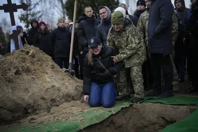 Anna Korostenska, de 24 años, se arrodilla ante la tumba de su prometido Oleksii Zavadskyi, un militar ucraniano que murió en combate el 15 de enero en Bájmut, durante su funeral el jueves 19 de enero de 2023 en Bucha, Ucrania. (AP Foto/Daniel Cole)