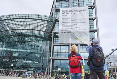 Activistas de Greenpeace cuelgan una gran pancarta con la leyenda "Se busca canciller climático" en la estación ferroviaria principal de Berlón, viernes 17 de setiembre de 2021. Las elecciones parlamentarias están convocasdas para el 26 de setiembre. (Annette Riedl/dpa via AP)