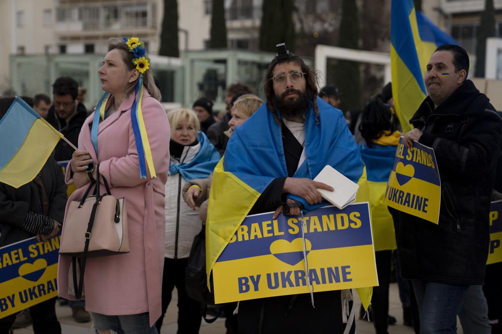 La gente se reúne en la plaza Habima en Tel Aviv, Israel, para ver al presidente ucraniano Volodymyr Zelenskyy en un discurso en video ante la Knesset, el parlamento de Israel, el domingo 20 de marzo de 2022. (AP Photo/Maya Alleruzzo) El primer ministro israelí, Naftali Bennett, preside el semanario reunión de gabinete en Jerusalén, domingo 20 de marzo de 2022. (AP Photo/Maya Alleruzzo, Pool)zo)