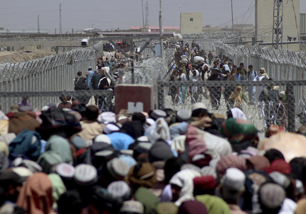 Stranded people crossing the border between Pakistan Afghanistan, in Chaman, Pakistan, Friday, Aug. 13, 2021. Pakistan opened its Chaman border crossing for people who had been stranded in recent weeks. Juma Khan, the Pakistan border town's deputy commissioner, said the crossing was reopened following talks with the Taliban. (AP Photo/Jafar Khan)