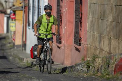 Bonifaz Díaz pedalea por las calles de Quetzaltenango, Guatemala, llevando comida a niños necesitados el 30 de enero del 2021. Díaz ha recorrido miles de kilómetros por las montañas de Guatemala cambiando libros donados por alimentos para los niños. (Henning Sac v{ia AP)