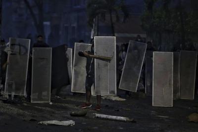 Los manifestantes se protegen con escudos improvisados en enfrentamientos con la policía durante un paro nacional para protestar por la reforma tributaria propuesta por el gobierno del presidente Iván Duque, en Cali, Colombia, el viernes 30 de abril de 2021. (AP Foto/Andrés González)