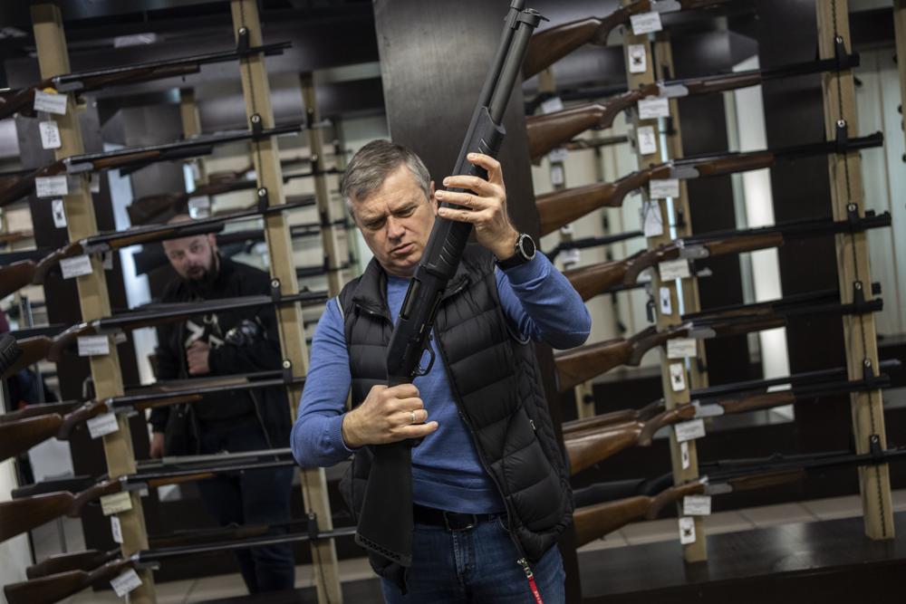 A customer checks his rifle in a gun shop in Lviv, western Ukraine, Wednesday, March 23, 2022. The rush for guns and gun training continued in the western city of Lviv. The state of war has streamlined gun purchasing in Ukraine, now simplified. (AP Photo/Bernat Armangue)