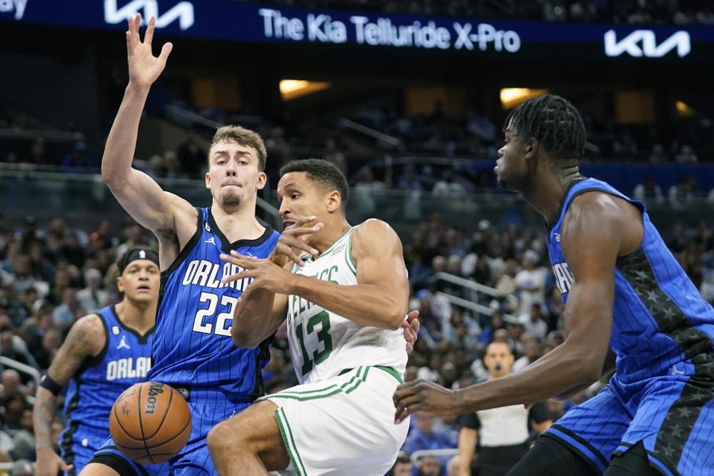 Boston Celtics' Malcolm Brogdon (13) loses the ball as he tries to go up to shoot between Orlando Magic's Franz Wagner (22) and Mo Bamba, right, during the first half of an NBA basketball game, Saturday, Oct. 22, 2022, in Orlando, Fla. (AP Photo/John Raoux)