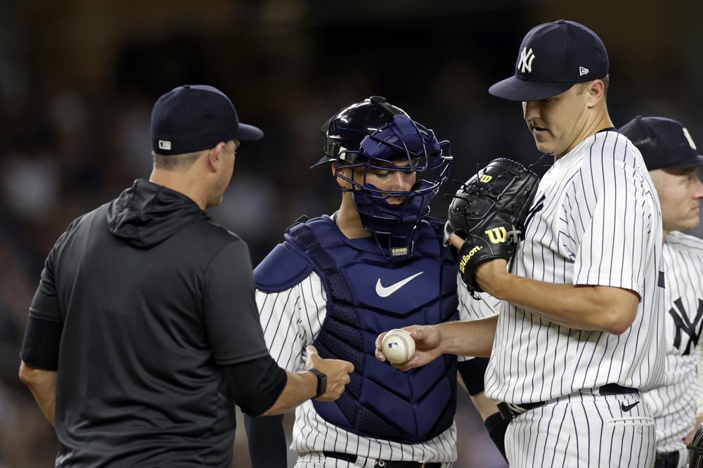 El lanzador de los Yankees de Nueva York, Jameson Taillon, entrega el balón al manager Aaron Boone cuando lo sacan del juego de béisbol contra los Azulejos de Toronto durante la sexta entrada el viernes 19 de agosto de 2022 en Nueva York. (Foto AP/Adam Hunger)