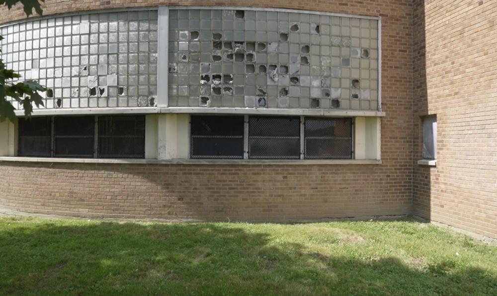 Broken windows are seen outside Cody High School in Detroit on Friday, Aug. 20, 2021. Like other school systems, Detroit is caught between the Biden administration's lofty aspirations and bleak realities. The district is using some of the government money to hire tutors, expand mental health services and cut class sizes. But at least half of its $1.3 billion windfall is being set aside to make long-neglected repairs. (AP Photo/Carlos Osorio)
