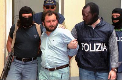 ARCHIVO - En esta foto de archivo del 21 de mayo de 1964, el mafioso Giovanni Brusca escoltado por policías llega al cuartel policial en Palermo, Sicilia. Brusca, de 64 años, quedó en libertad, se informó el jueves 3 de junio de 2021, luego de purgar 25 años de una cadena perpetua por algunos de los crímenes más odiosos de la Cosa Nostra, como el asesinato del principal fiscal antimafia en 1992 y el secuestro y asesinato del hijo de 11 años de un arrepentido de la Mafia cuyo cuerpo fue disuelto en un barril de ácido. Su libertad provocó indignación en Italia. (AP Foto/Alessandro Fucarini)