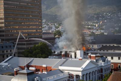 Bomberos lanzan agua sobre las llamas que salen de un edificio del Parlamento de Sudáfrica, el domingo 2 de enero de 2022, en Ciudad del Cabo. (AP Foto/Jerome Delay)