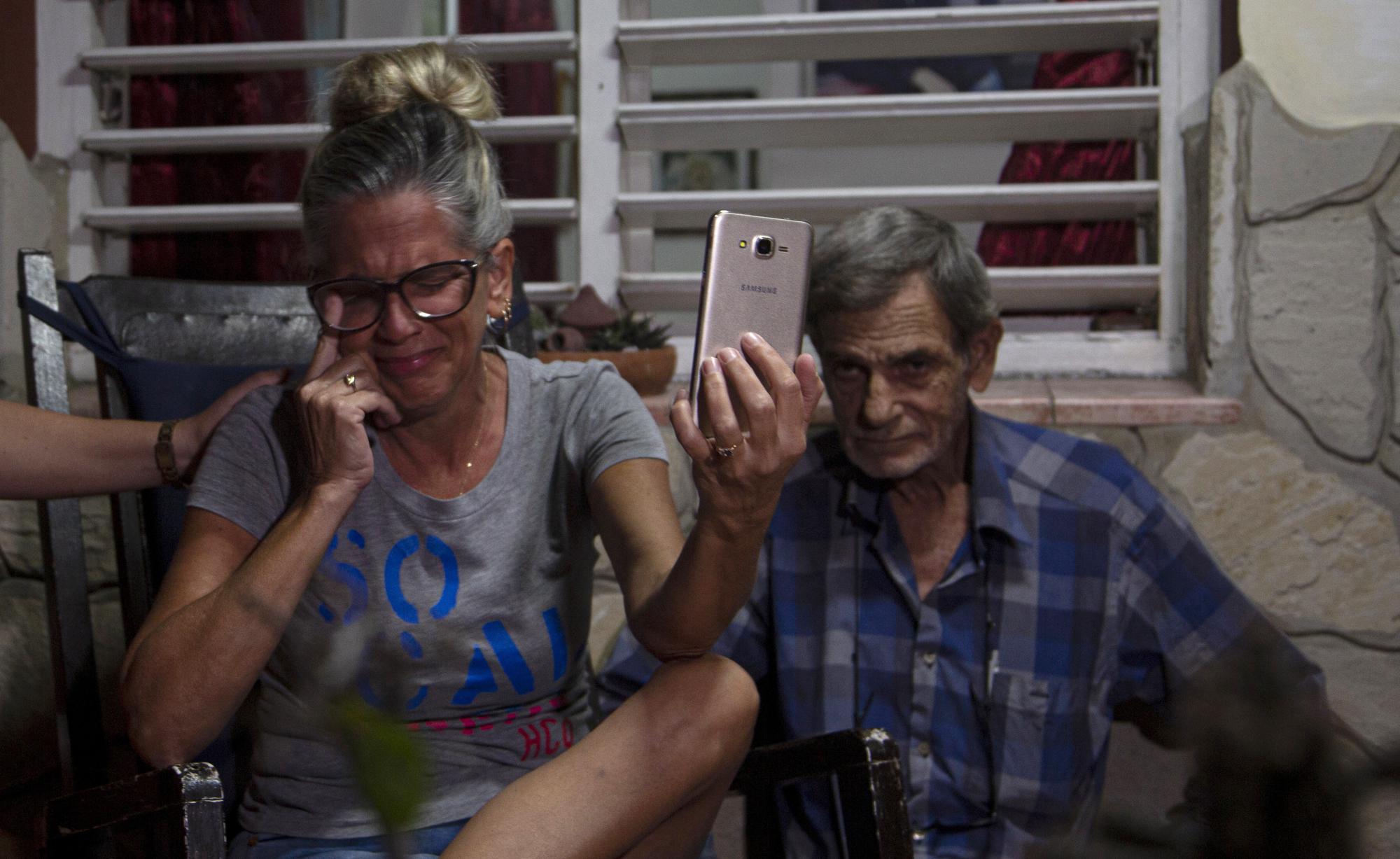 Marialys Gonzalez Lopez and her father, Alejandro Gonzalez Lopez, hold a video call with her daughters Merlyn and Melanie, and Melanie's daughter, Madisson, from their home in Havana, Cuba, Tuesday, Jan. 3, 2023. The sisters arrived days earlier in the U.S., after a three-week journey through Central America and Mexico. During that time, their mother clung to texts and photos as signs they were okay. (AP Photo/Ismael Francisco)