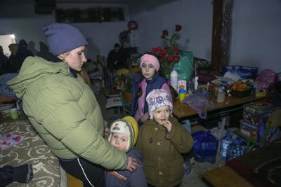 Una mujer y niños se arrastraron por los bombardeos en un refugio antiaéreo escolar en la aldea de Sartana, que está bajo el control del Gobierno de la República Popular de Donetsk, a 17 km (11 millas) al noreste de Mariupol, al este de Ucrania, el miércoles 16 de marzo de 2022. (AP Photo/Alexei Alexandrov)