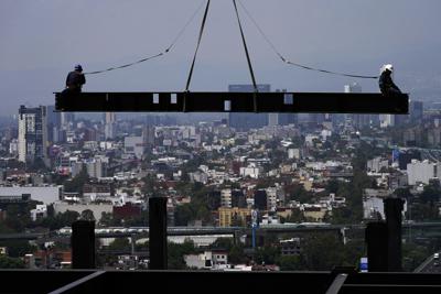 ARCHIVO - Obreros de la construcción cabalgan sobre una viga en un edificio residencial en Ciudad de México, 17 de junio de 2022. El Senado mexicano el miércoles 26 de octubre de 2022 aprobó un proyecto de ley para eliminar el horario de verano, poniendo fin al cambio de hora que se realiza dos veces al año. (AP Foto/Marco Ugarte, File)