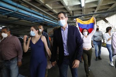 El líder opositor Juan Guaidó y su esposa Fabiana Rosales caminan en el estacionamiento del edificio residencial en el que viven luego de una conferencia de prensa improvisada el lunes 12 de julio de 2021 en Caracas, Venezuela. (AP Foto/Ariana Cubillos)