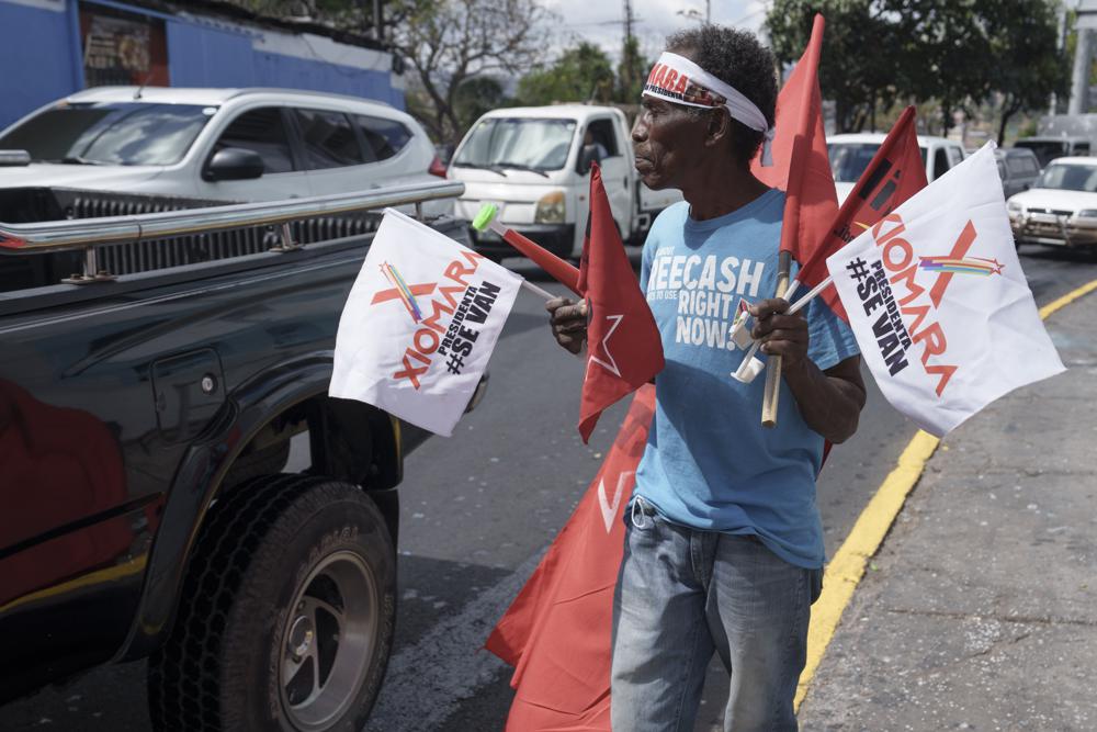 Vendor Oscar Prado hawks flags promoting President-elect Xiomara Castro outside the National Stadium in Tegucigalpa, Honduras, Wednesday, Jan. 26, 2022. Castro, Honduras' first female president, is scheduled to be sworn in on Thursday, Jan. 27. (AP Photo/Moises Castillo)