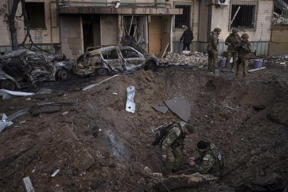 A Ukrainian bomb squad inspect the site of an explosion after bombing in Kyiv, Ukraine, Sunday, March 20, 2022. (AP Photo/Felipe Dana)
