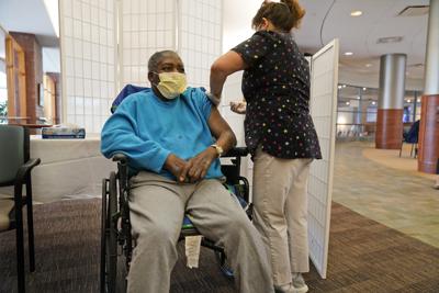 Edward Williams, de 62 años, interno de la residencia Hebrew Home en Riverdale, recibe una dosis de refuerzo de la vacuna contra el COVID-19 en Nueva York, el lunes 27 de septiembre de 2021. (AP Foto/Seth Wenig)