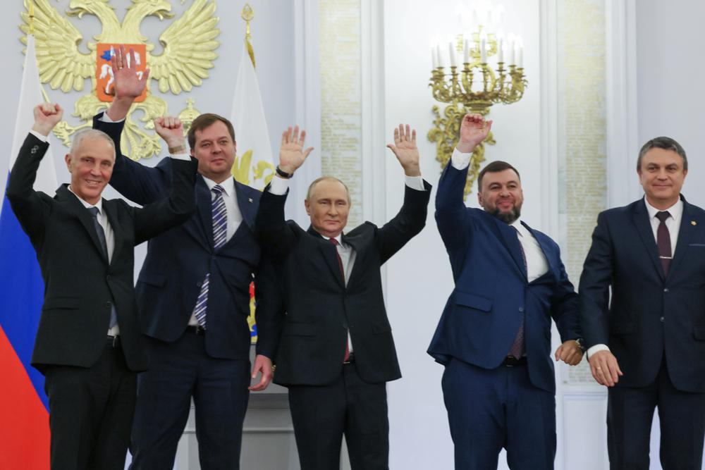 From left, Moscow-appointed head of Kherson Region Vladimir Saldo, Moscow-appointed head of Zaporizhzhia region Yevgeny Balitsky, Russian President Vladimir Putin, center, Denis Pushilin, the leader of the Donetsk People's Republic and Leonid Pasechnik, leader of self-proclaimed Luhansk People's Republic wave during a ceremony to sign the treaties for four regions of Ukraine to join Russia, at the Kremlin, Moscow, Friday, Sept. 30, 2022. The signing of the treaties making the four regions part of Russia follows the completion of the Kremlin-orchestrated "referendums." (Mikhail Metzel, Sputnik, Kremlin Pool Photo via AP)