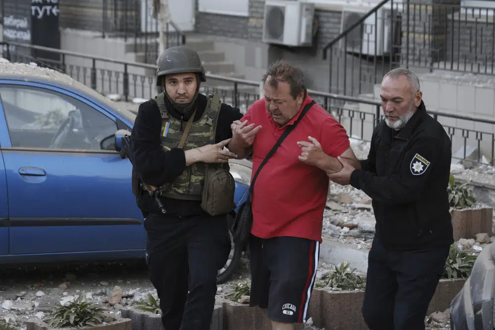 Agentes de policía ayudan a un hombre herido a salir de un edificio residencial y dirigirse a una ambulancia durante una ola de bombardeos en Kiev, Ucrania, el 30 de mayo de 2023. (AP Foto/Alex Babenko)