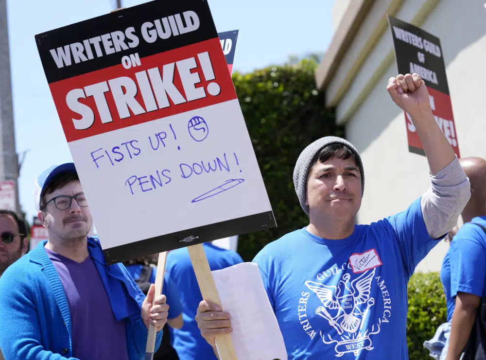 El integrante del Sindicato de Guionistas de Estados Unidos rama Oeste, Víctor Dueñas, derecha, se manifiesta en la entrada de Paramount Pictures, el martes 2 de mayo de 2023, en Los Angeles. La primera huelga de Hollywood en 15 años comenzó el martes cuando las presiones económicas de la era del streaming llevaron a guionistas de cine y televisión sindicalizados a protestar por mejores salarios. (Foto AP/Chris Pizzello)