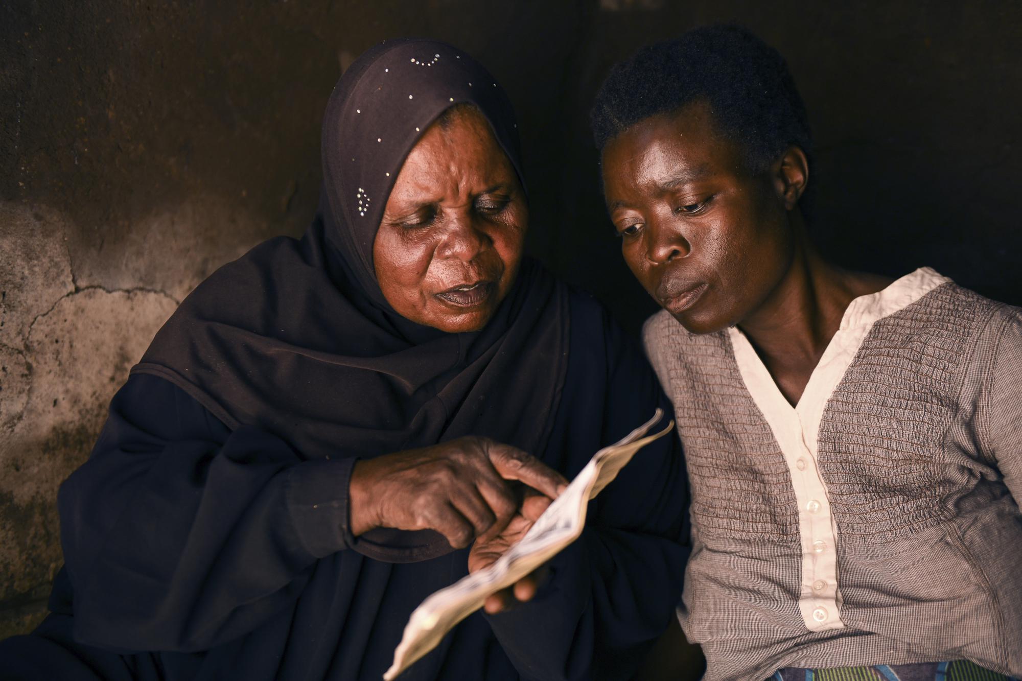 Lucy Mbewe, a traditional birth attendant looks at a pregnant woman's health passport at her home, in Simika Village, Chiradzulu, southern Malawi, Sunday, May 23, 2021. Health officials in Malawi say fewer women are getting prenatal care amid the COVID-19 pandemic. At risk are the developing country's gains on its poor rate of maternal deaths. (AP Photo/Thoko Chikondi)